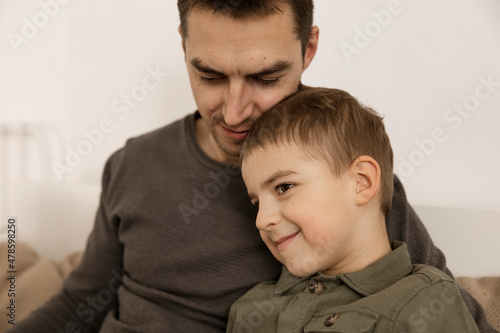Portrait of father and his son. Dad loves his boy. Young attractive man and little caucasian kid have fun together. Interior and clothes in natural earth colors. Cozy environment. © Creative_Bird