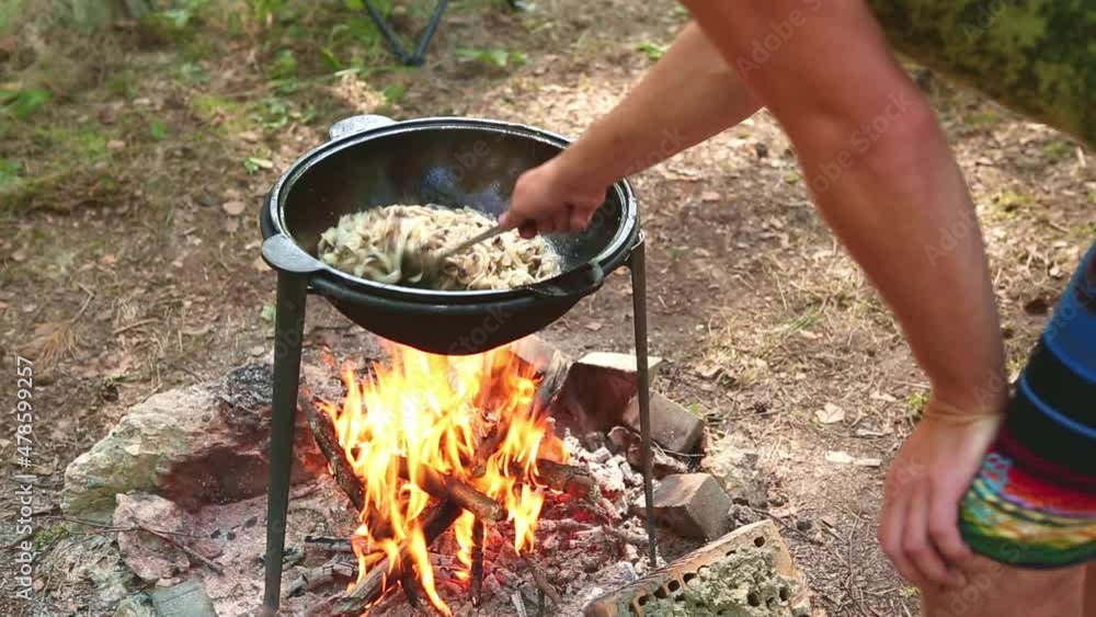 Cooking on a campfire in a cauldron outdoor in the woods camping on a hike. Stirring food in a camping kazan, smoke and aroma on an open fire. Outdoor recreation Cooking on a campfire in a cauldron outdoor in the woods camping on a hike. Stirring food in a camping kazan, smoke and aroma on an open fire. Outdoor recreation