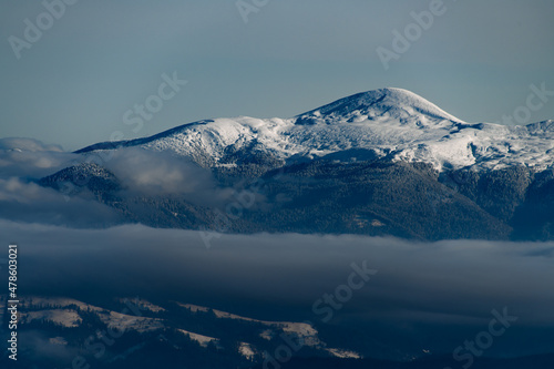 glorious aerial view of snow covered mountain top and picturesque winter mountain landscape with coniferous trees and fog