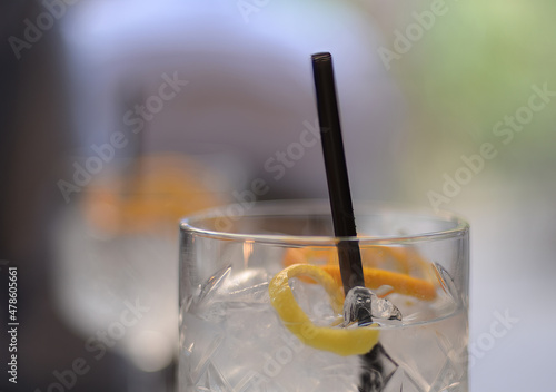 Selective focus on a crystal glass of gin and tonic with lemon, orange and black straw