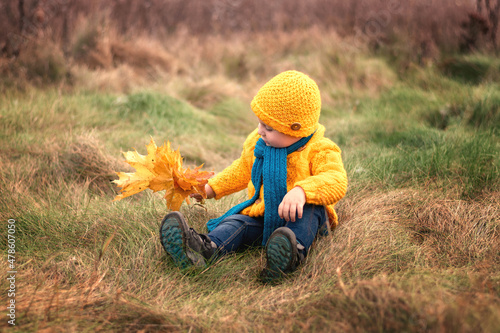 A two-year-old boy wearing knitted clothes and a scarf .