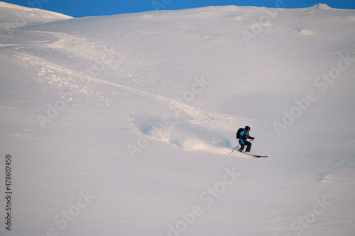 active freerider rides down white powdery snow of mountain slope
