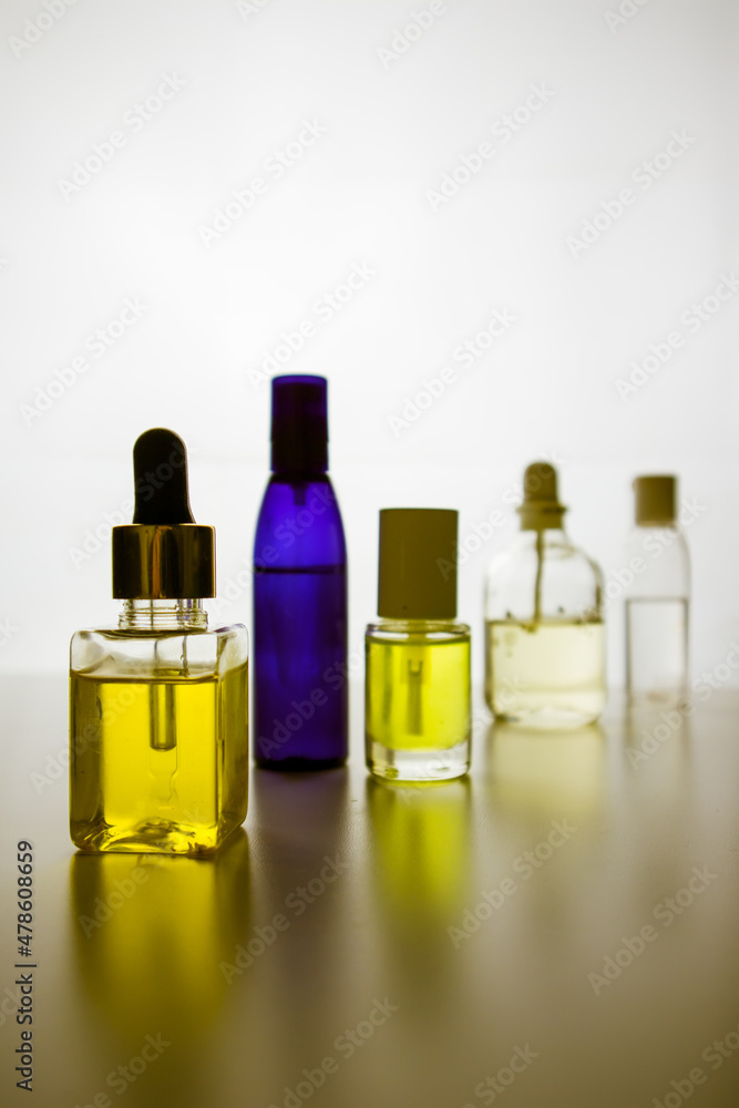 Silhouettes of small yellow and blue bottles with natural cosmetics, essential oil, face body skin care aroma oils on white background. Wellness, spa composition. Various capacities, limpid glassware.