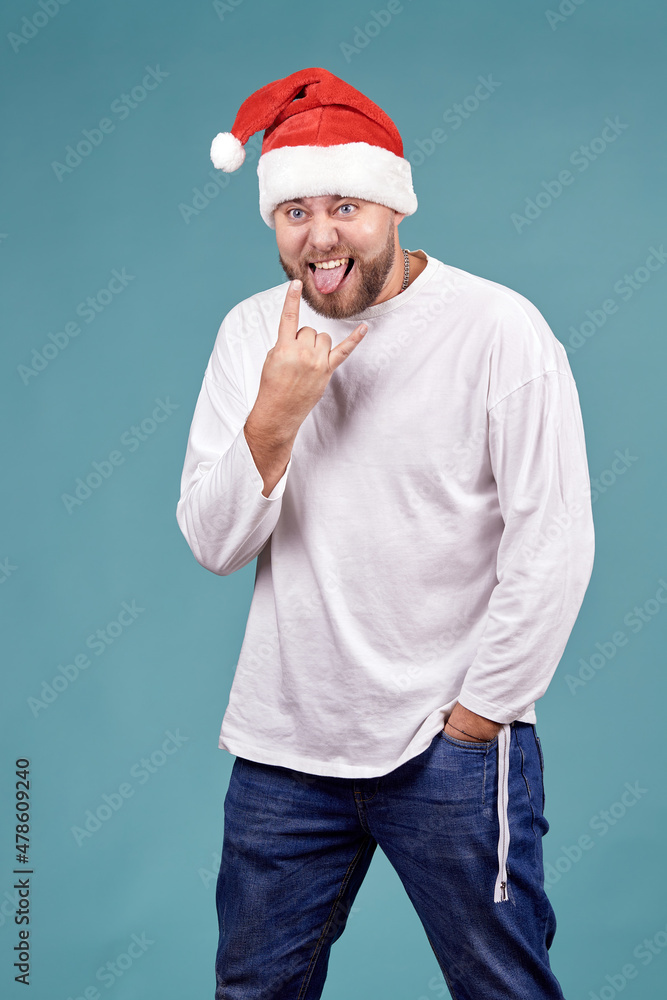 a young man in a Santa hat poses showing a rocker gesture