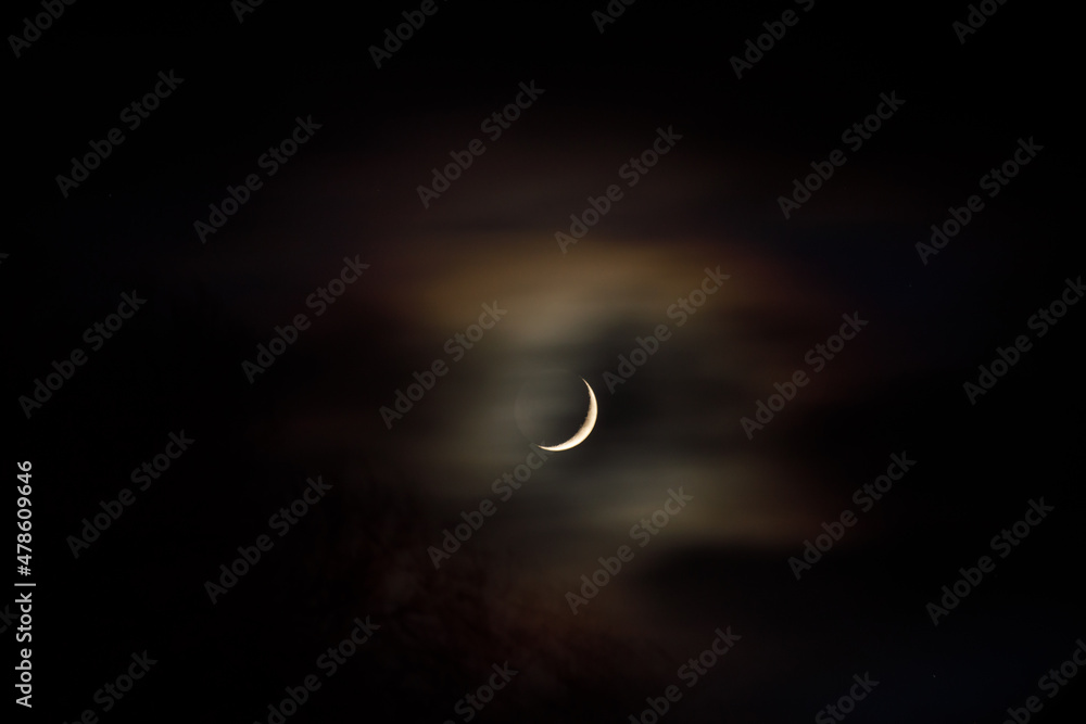 waxing crescent moon in the sky behind a veil of clouds waxing crescent moon in the sky behind a veil of clouds