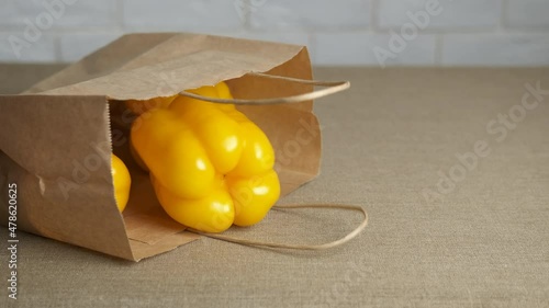 Ripe peppers in a bag. A woman takes out the pappers from the craft bag on the table. photo