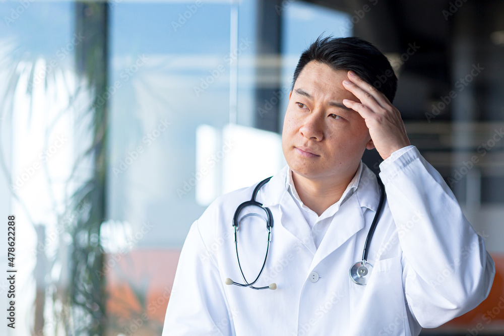 tired asian doctor, depressed man working in a modern clinic tired asian doctor, depressed man working in a modern clinic