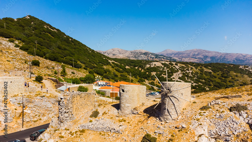 a panoramic view of the ancient centuries-old mills against the backdrop of mountains and olive groves of Crete filmed from a drone.