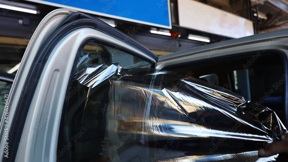 Hand pulling the old film out of the car windshield. Peeling off the