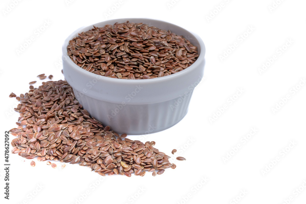 Flax seeds in a white ceramic cup on a white background. Flax seeds in a white ceramic cup on a white background.