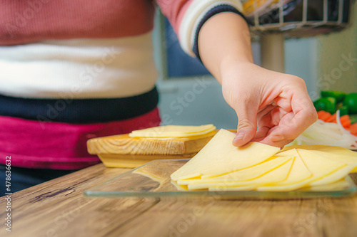 Slices of yellow cheese on a glass plate on top of a wooden table