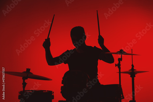 Obraz na plátně Silhouette of a young man playing drums on a red background
