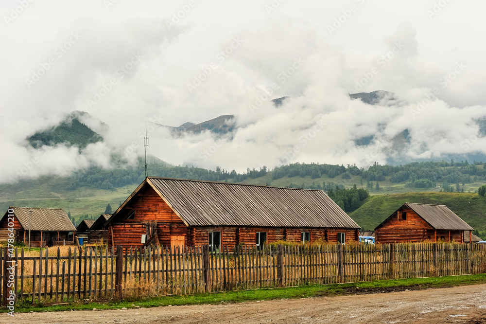 Mountain village, wooden houses, mountains, forests, natural scenery, under the background of cloudy weather. In Altay, Xinjiang, China.
