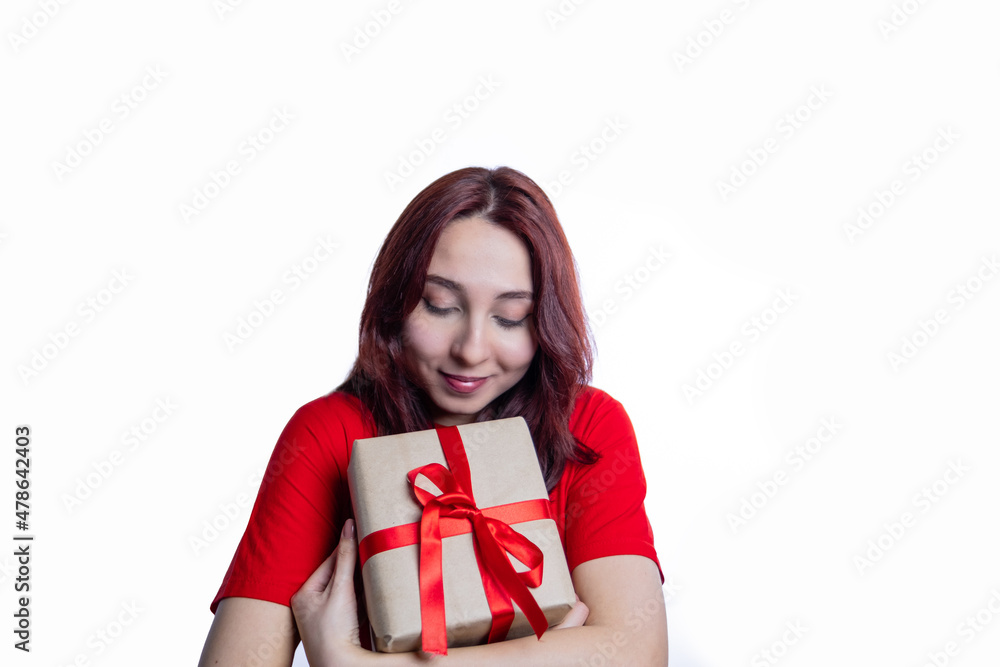 Fototapeta premium Caucasian woman in red shirt with closed eyes holding gift box 