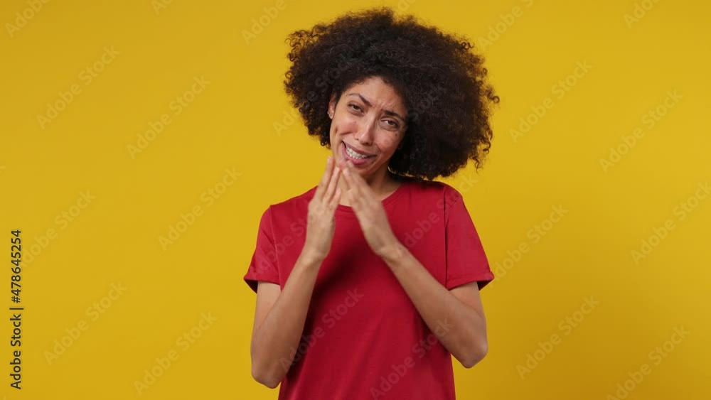 Pleading fun young black woman 20s years old wears red t-shirt hold hands folded in prayer begging about something making wish keep fingers crossed isolated on plain yellow background studio portrait Pleading fun young black woman 20s years old wears red t-shirt hold hands folded in prayer begging about something making wish keep fingers crossed isolated on plain yellow background studio portrait