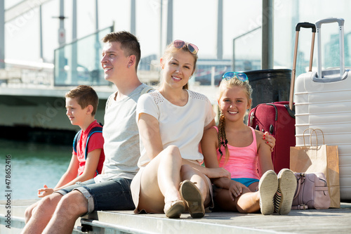 Positive family of four tourists with suitcase relaxing on embankment Fototapet