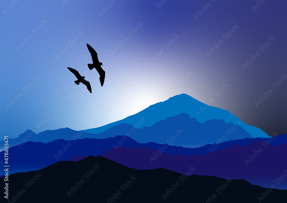 Flying black birds over blue mountains in the evening