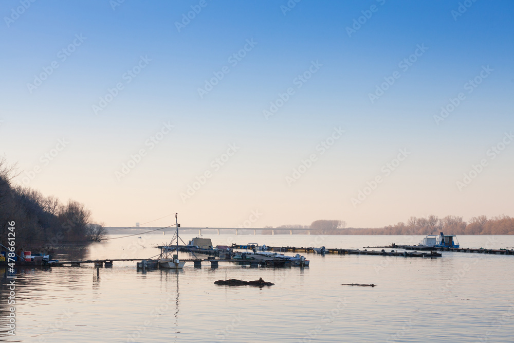 Boats & ships, fishing ships and boats  tanding anchored on the riverbanks of the river Dabubein Zemun, a suburb of Belgrade, Serbia during a sunny afternoon with a bridge behind...