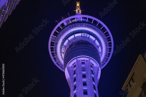 Fotografering Night scene tall circular tower illuminated blue viewed through strings of decorative fairy lights