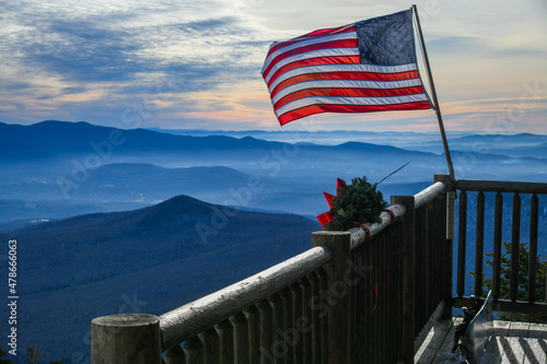 American flag waiving at the ski patrol house on the beautiful winter day at the Stowe Mountain Ski Resort, Vermont. Top view with mountains silhouette on the background.