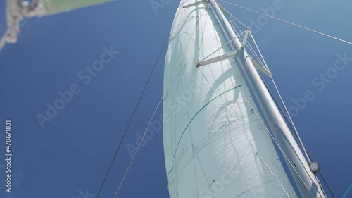 the sail fluttering from wind in sunny day. adventure journey mainsail of sailboat moving in the sea travel trip. copy space. ant view of sailing mast struts. foremast standing in windy day. photo