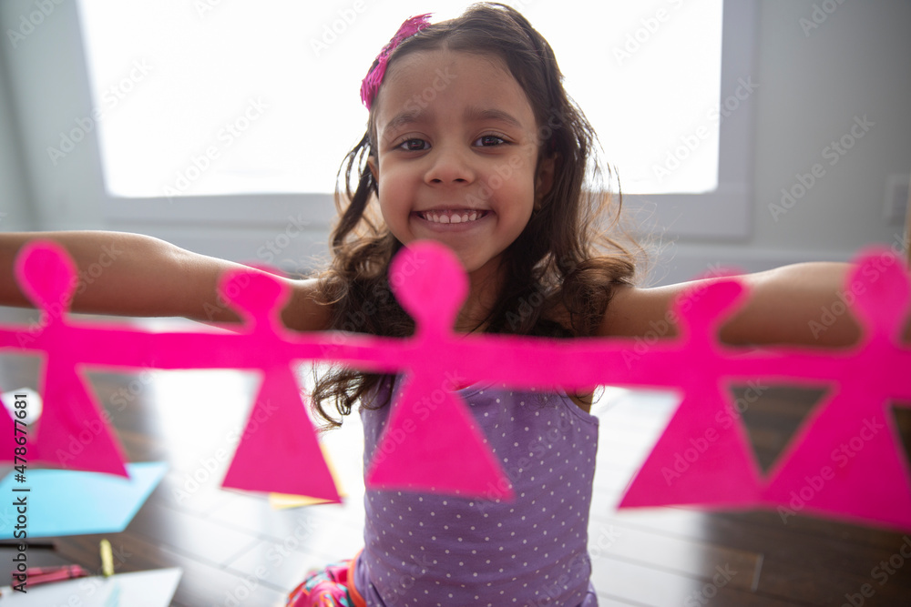 Girl holding paper doll chain at home Stock Photo Adobe Stock