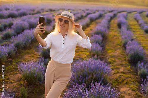Fototapeta Naklejka Na Ścianę i Meble -  Young blond woman traveller wearing straw hat in lavender field surrounded with lavender flowers.