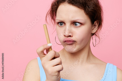 cute girl in a white t-shirt with a pen in his hands emotions pink background