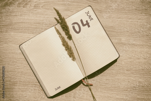 june 4. 4th day of month, calendar date.Blank pages of notebook are beige, with dried spikelets. Concept of day of year, time planner, summer month photo