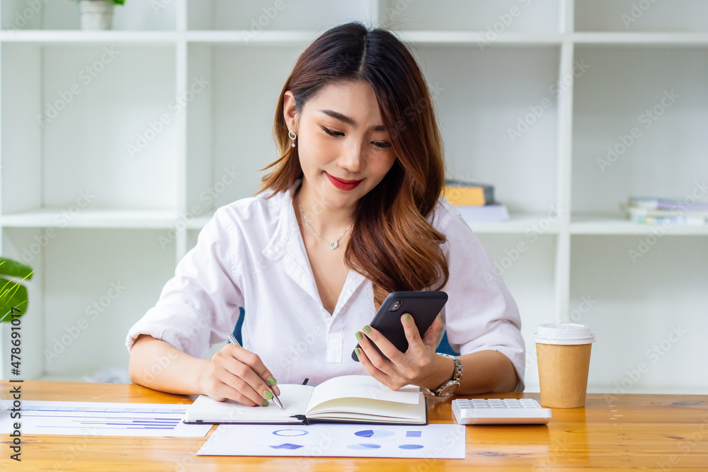 Businesswoman looking at last year's company sales data on the phone, woman sitting in a chair looking at financial documents, accountant checking company numbers, new business concept. Businesswoman looking at last year's company sales data on the phone, woman sitting in a chair looking at financial documents, accountant checking company numbers, new business concept.