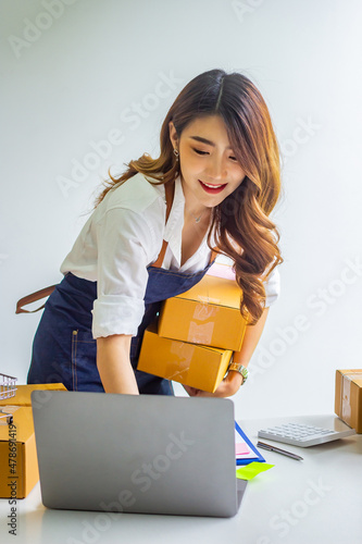 Small business owner looking at company's past online sales, cropped image of woman holding her own box for delivery at online sales office, merchandising concept and modern businessman.