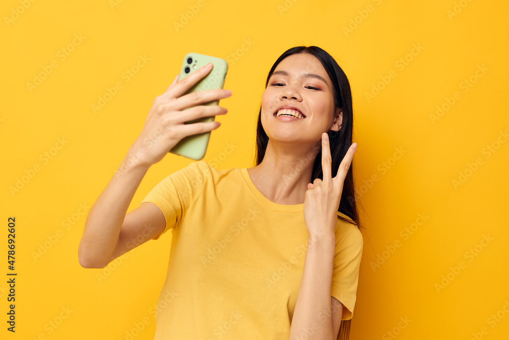 pretty brunette with a phone in her hands makes a selfie yellow background unaltered pretty brunette with a phone in her hands makes a selfie yellow background unaltered