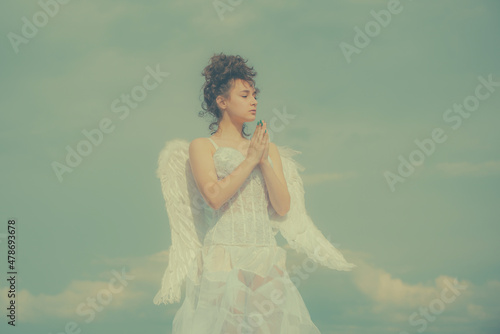 Valentines angel teen praying. Angel teen in heaven. Teenage angel girl with wings, copy space on sky.