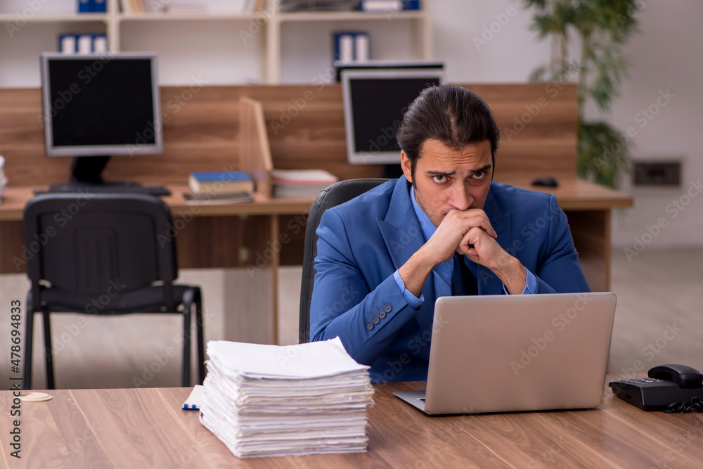 Young male employee and a lot of work in the office Young male employee and a lot of work in the office