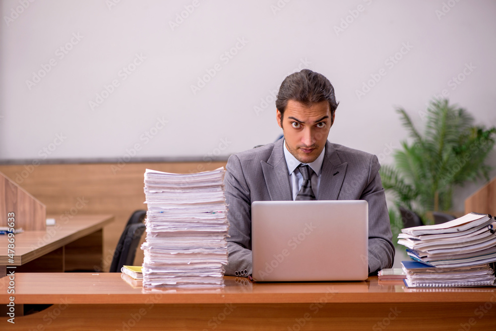 Young male employee and too much work in the office Young male employee and too much work in the office