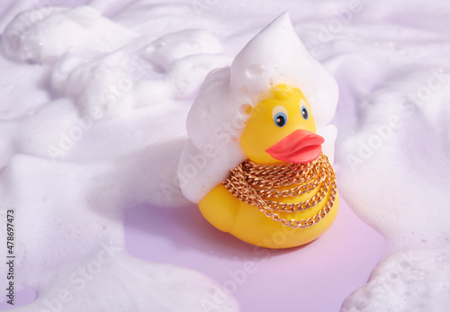 Yellow rubber duck with gold chain and foam on head and around. Positive shower mood. photo