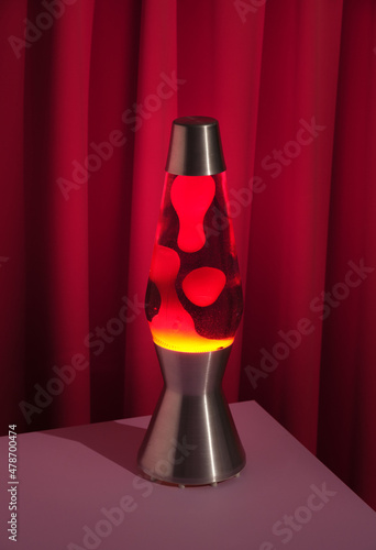 Table lava lamp with changing dynamic traceries. Red textile background. Image of youth and romantic passionate feelings.