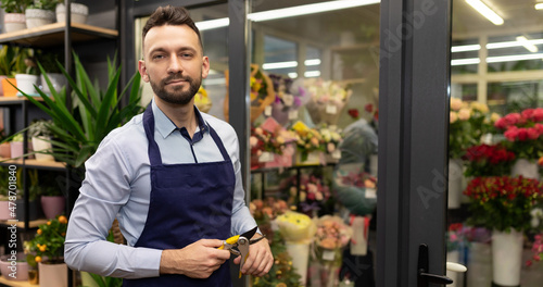 attractive male florist next to refrigerator with fresh fresh flowers