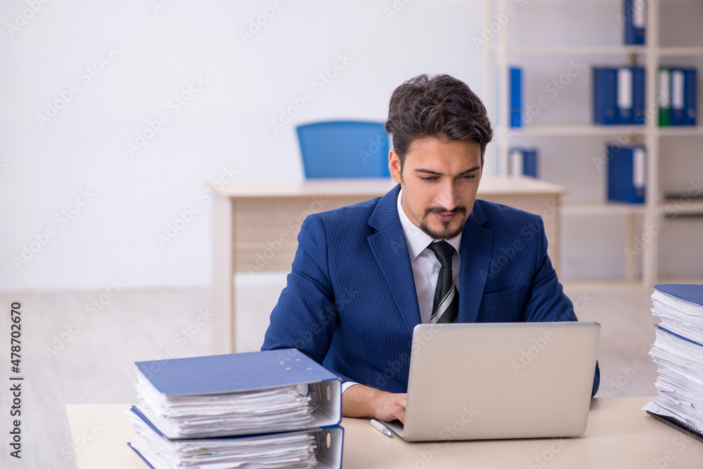Young male employee and too much work in the office Young male employee and too much work in the office