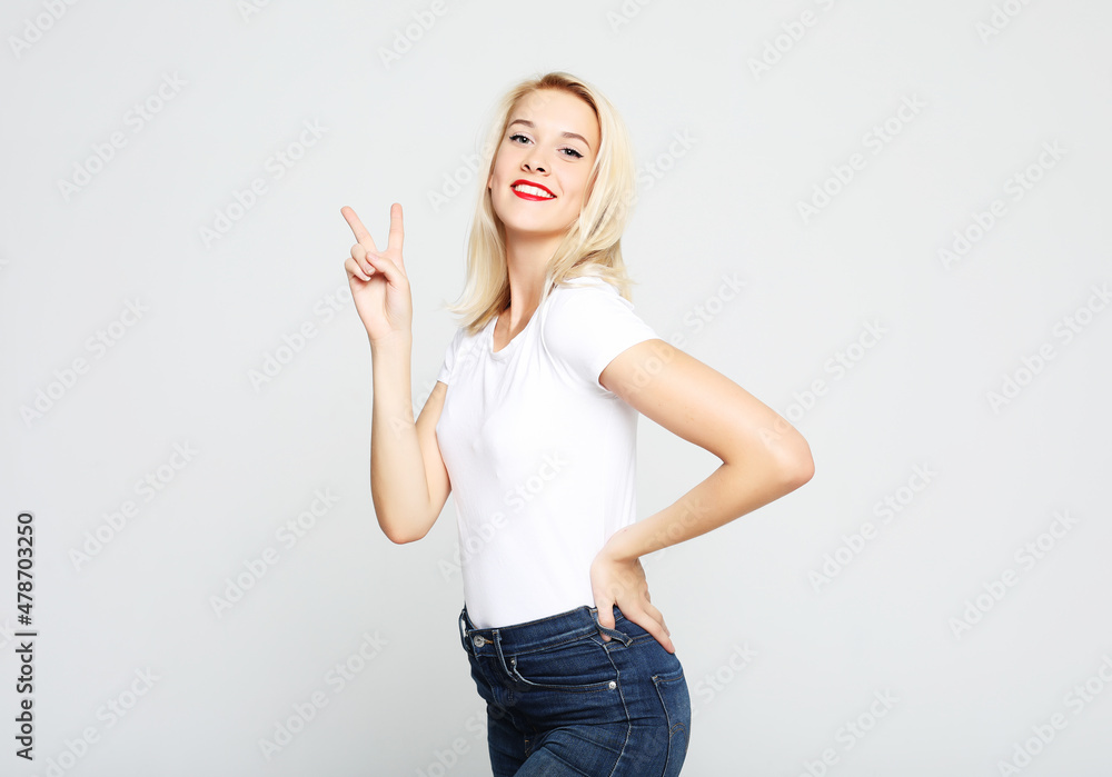 gorgeous woman looking at camera with smile and showing peace sign with fingers gorgeous woman looking at camera with smile and showing peace sign with fingers