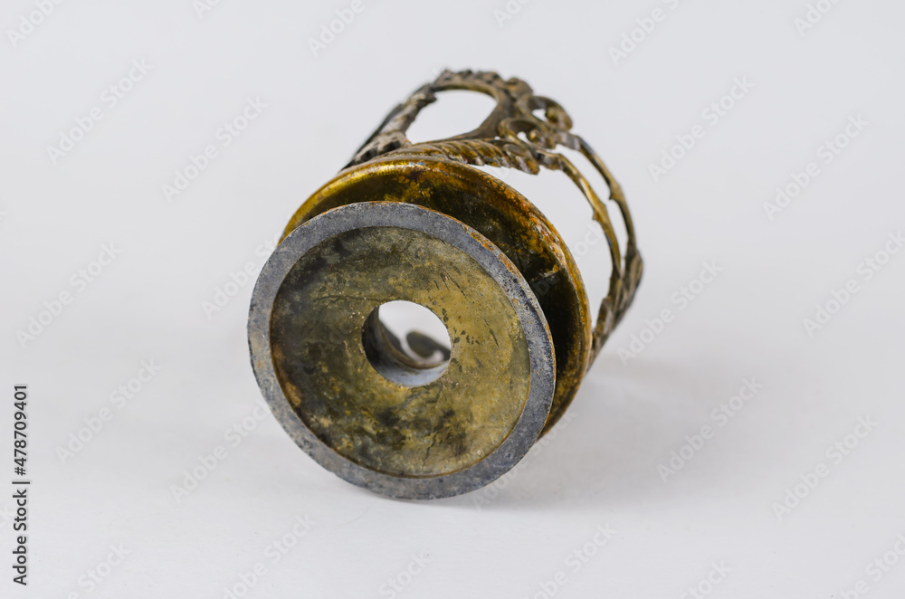 An old metal cupholder lies on a white background. An old metal cupholder lies on a white background.