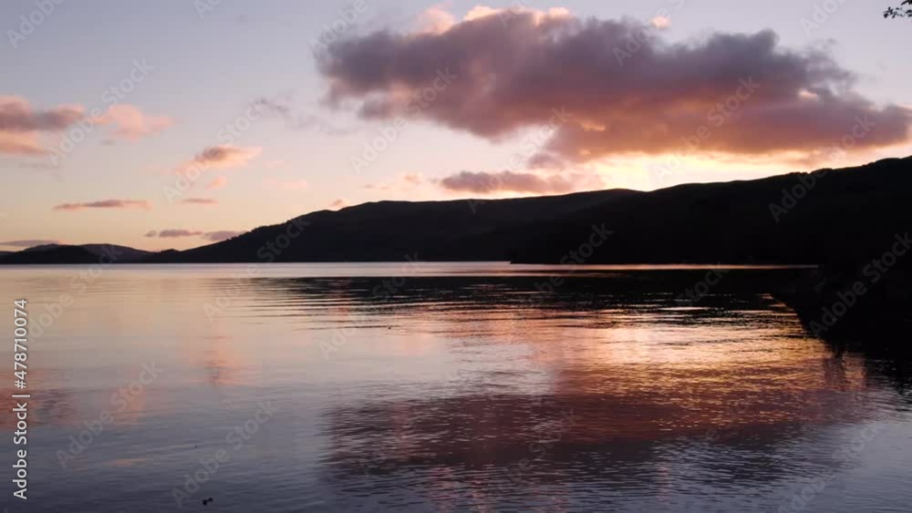 Aerial drone timelapse of a fiery golden sunset in autumn looking over Loch Lomond in Scotland with still, reflective water and clouds. Filmed in Loch Lomond and teh Trossachs National Park, Scotland Aerial drone timelapse of a fiery golden sunset in autumn looking over Loch Lomond in Scotland with still, reflective water and clouds. Filmed in Loch Lomond and teh Trossachs National Park, Scotland