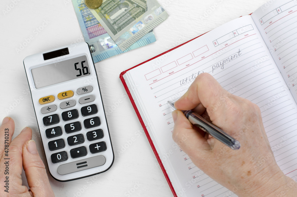 The pensioner calculates utility costs. Elderly woman hands are counting finances on a calculator The pensioner calculates utility costs. Elderly woman hands are counting finances on a calculator