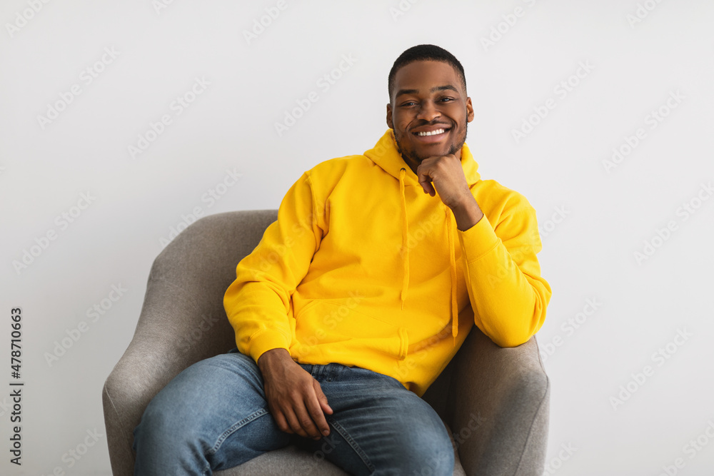 Black Man Posing Sitting In Armchair Posing Over Gray Background Black Man Posing Sitting In Armchair Posing Over Gray Background