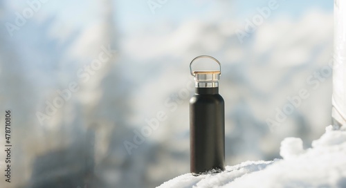 Thermos with tea or coffee on the snow