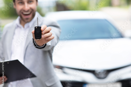 Businessman in suit showing or giving car key for customer getting new auto © Prostock-studio