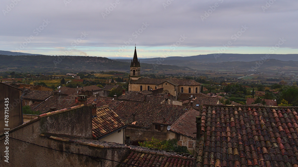 View over small village Bonnieux in low mountain range Luberon in Provence region, France on cloudy day in autumn season with characteristic buildings.