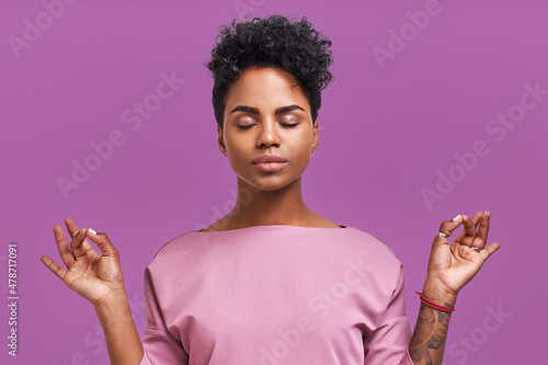 Calm woman relaxing meditating, no stress free relief at work concept, mindful peaceful young businesswoman or student practicing breathing yoga exercises on isolated over velvet violet background.