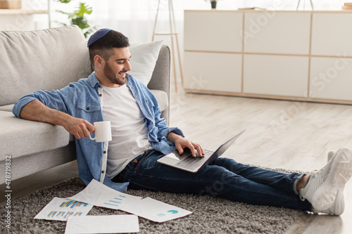 Man working on laptop at home on floor drinking coffee photo