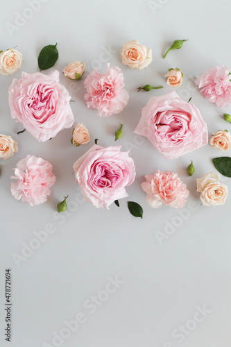 Beautiful flowers on a light gray background, roses, carnations, buds and greenery. Top view, copy space. Floral background, greeting card.